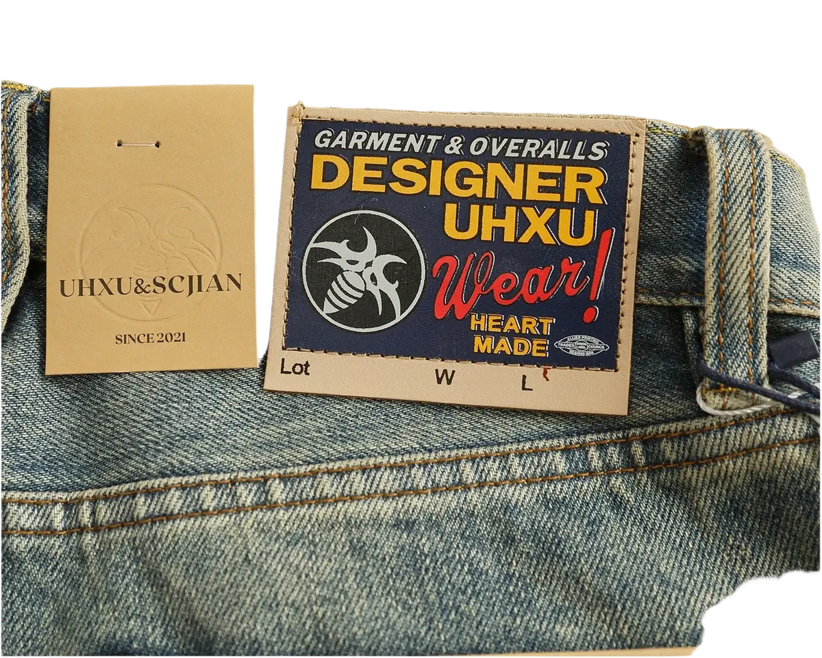 Blue denim distressed patchwork jeans with a bold colorful uhxu wear patch label and stylized bee logo on the back