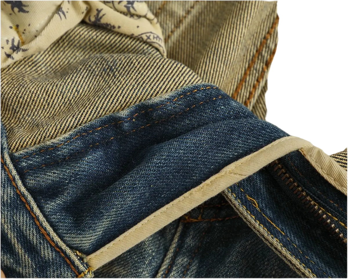 Distressed patchwork denim jeans for men in blue denim with beige stitching and subtle patterned lining visible