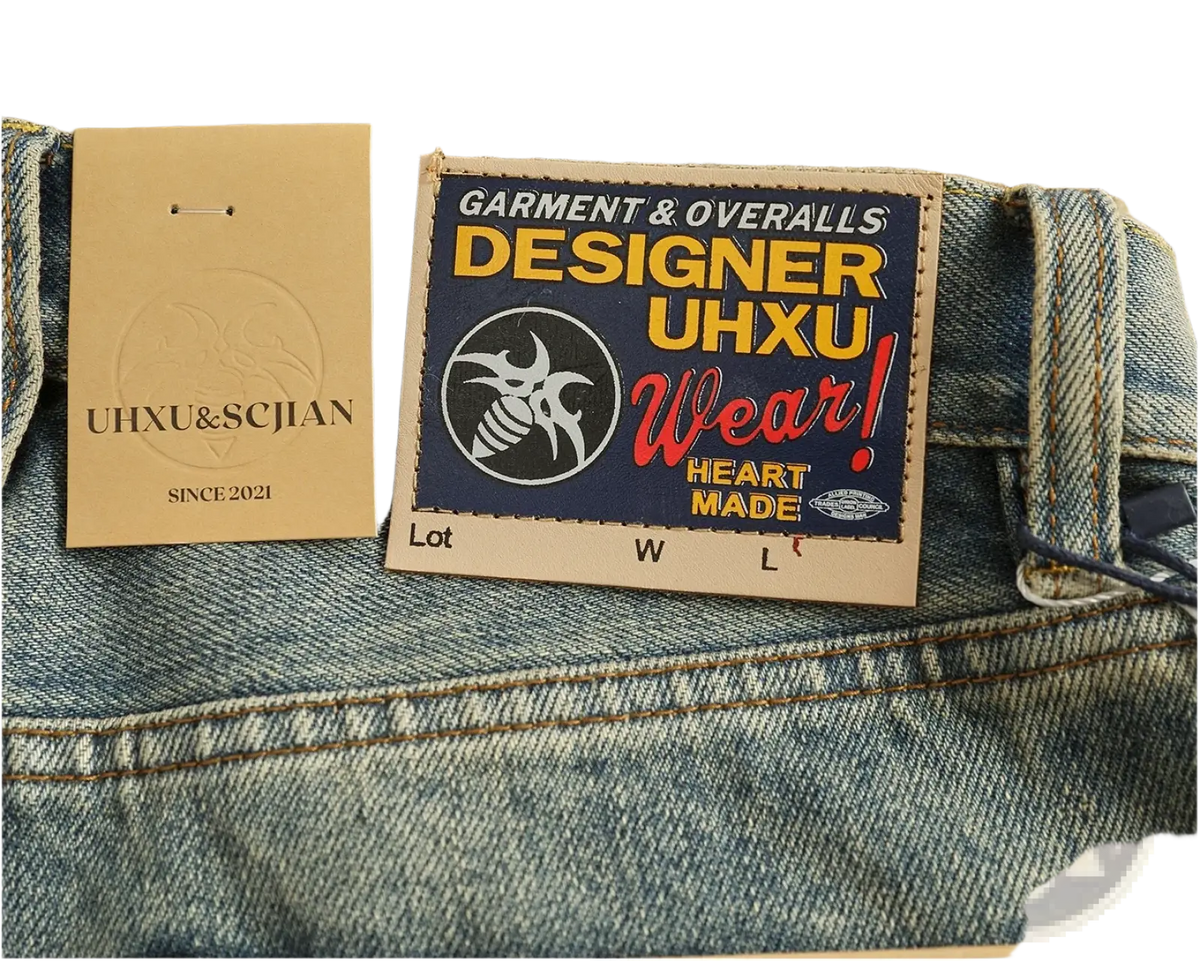 Blue denim distressed patchwork jeans with a bold colorful uhxu wear patch label and stylized bee logo on the back