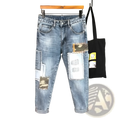 Distressed slim fit light wash denim jeans featuring distressed patches and camouflage fabric accents on the front