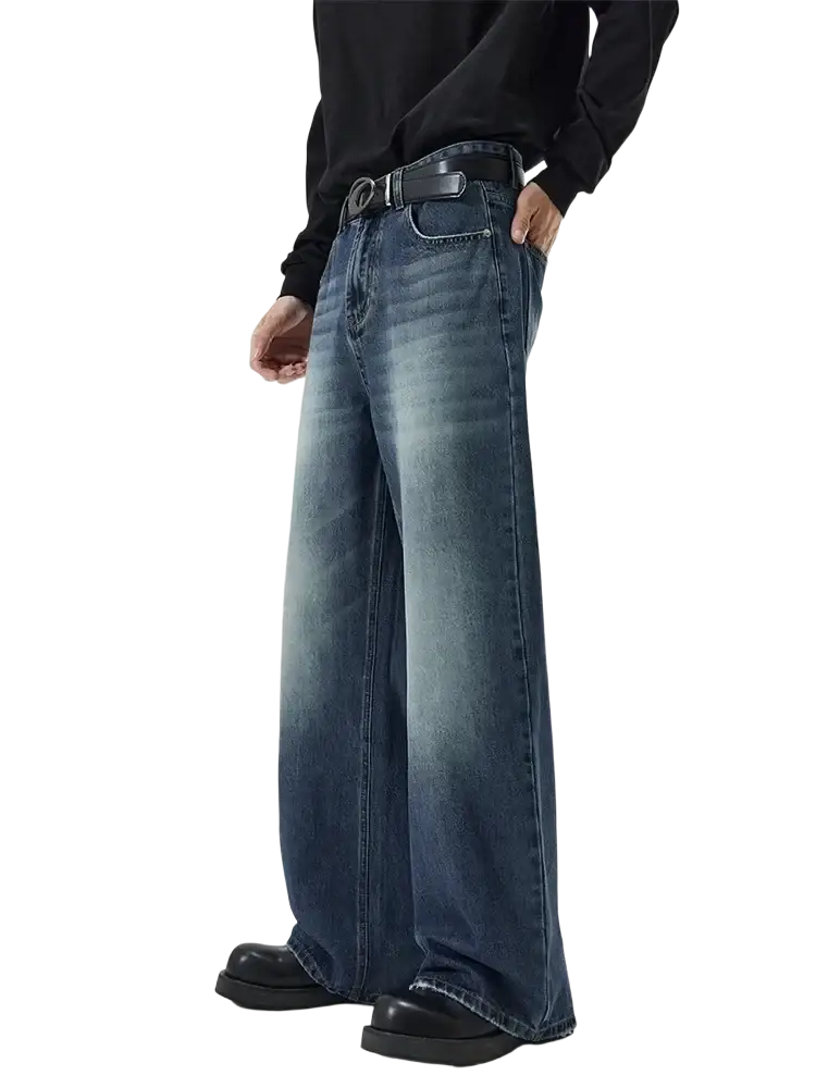 Distressed vintage baggy men denim jeans in faded blue wash with subtle whiskering and frayed hems in wide-leg style