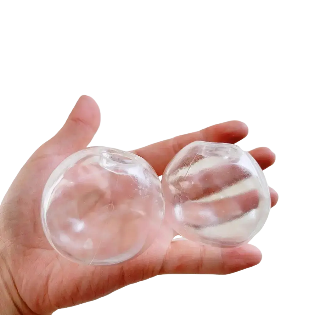 A hand holds two transparent diy handmade sensory squishy ball stress relief toys with a glossy finish