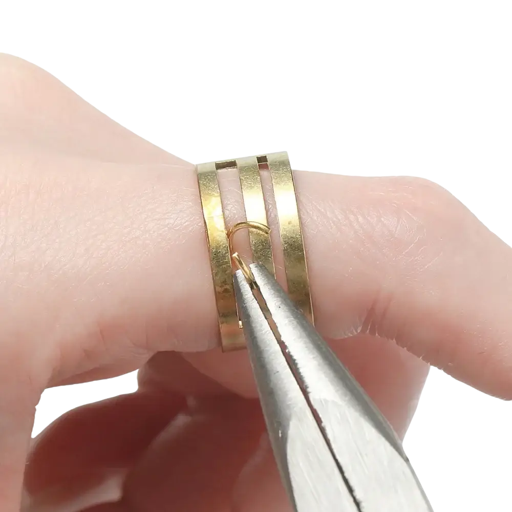 Gold-toned multi-band ring with textured finish being adjusted by pliers from diy jewelry making findings kit with tools