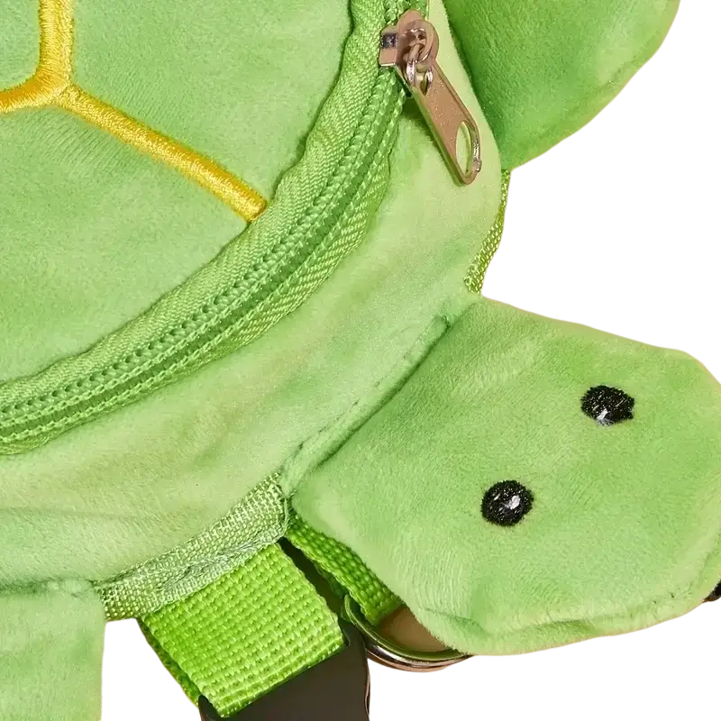 A plush green turtle-shaped dog backpack with yellow stitching and black embroidered eyes for pet carrying