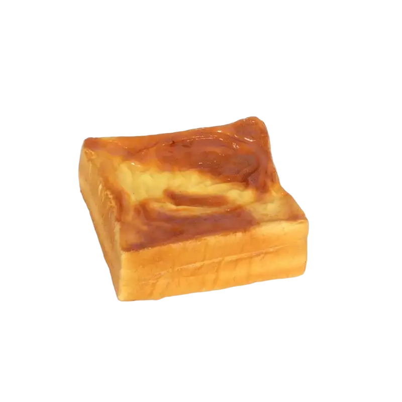 Dog bread slow rising squishy toy with golden brown caramelized top and soft fluffy interior on white square plate