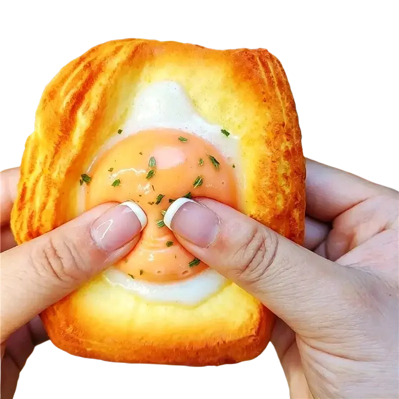 Dog bread slow rising squishy toy shaped like golden brown egg in puff pastry with flaky texture and green herb garnish