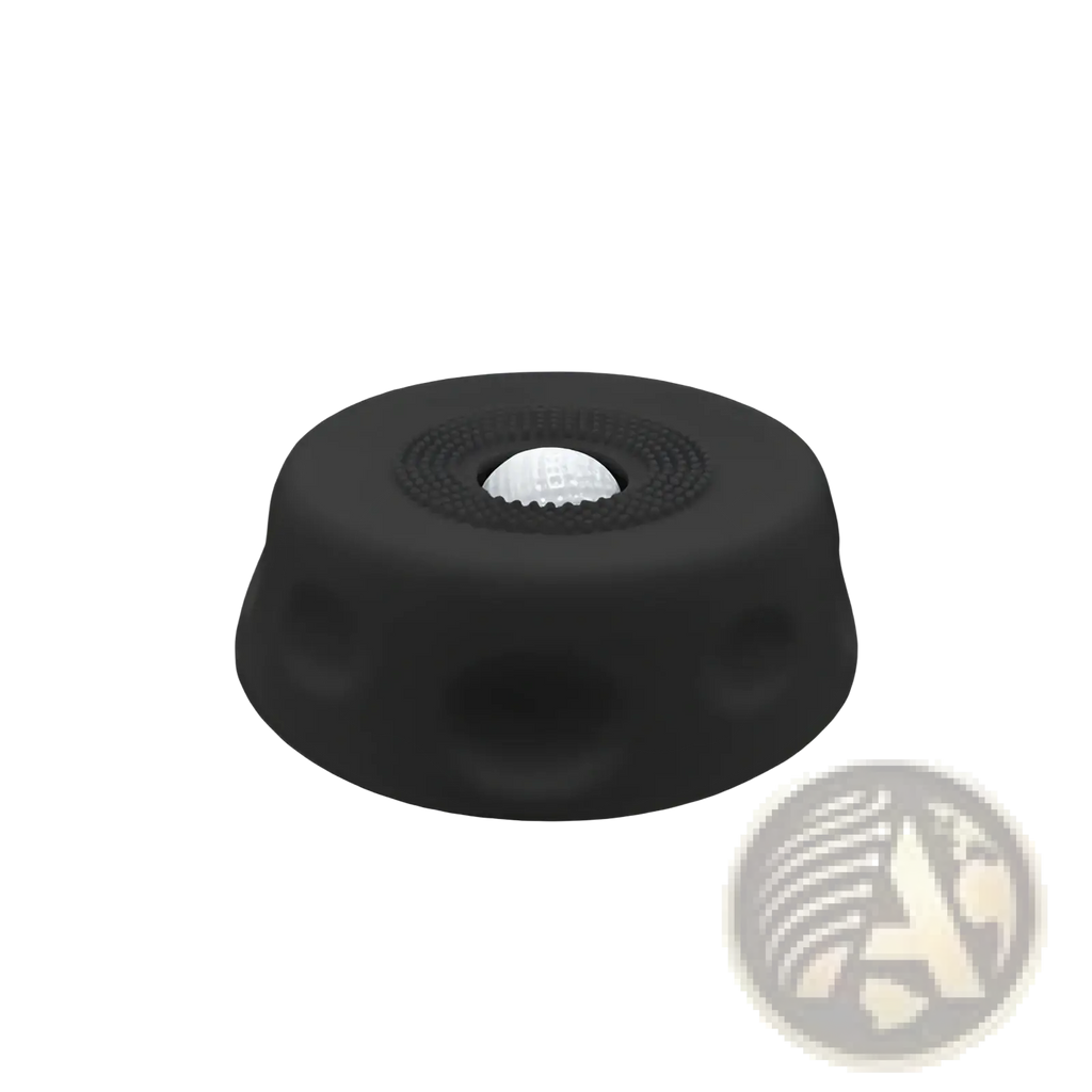 Black rubber grip cap with textured surface and central recess holding white golf ball for dog lick bowl slow feeder