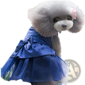A fluffy gray poodle wearing a royal blue rhinestone tulle dog wedding dress with satin bodice and pink flower accessory