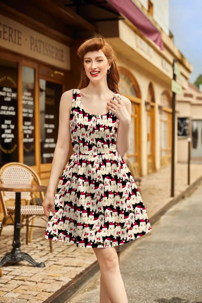 A sleeveless black and white cotton fit and flare dress with cartoon poodles wearing red santa hats holiday design
