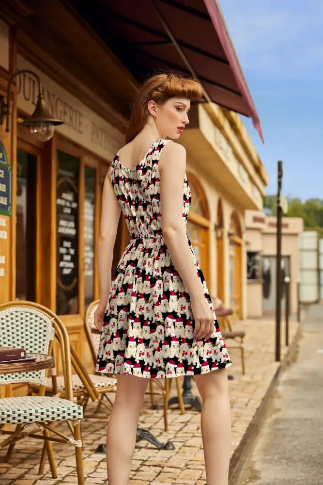A woman wears a black white and red cotton fit and flare holiday dress with cartoon poodle pattern and sleeveless design