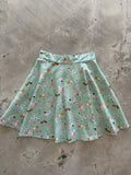 A pastel mint cotton skater skirt with a flared silhouette featuring dog breeds and floral accents in pink brown and white