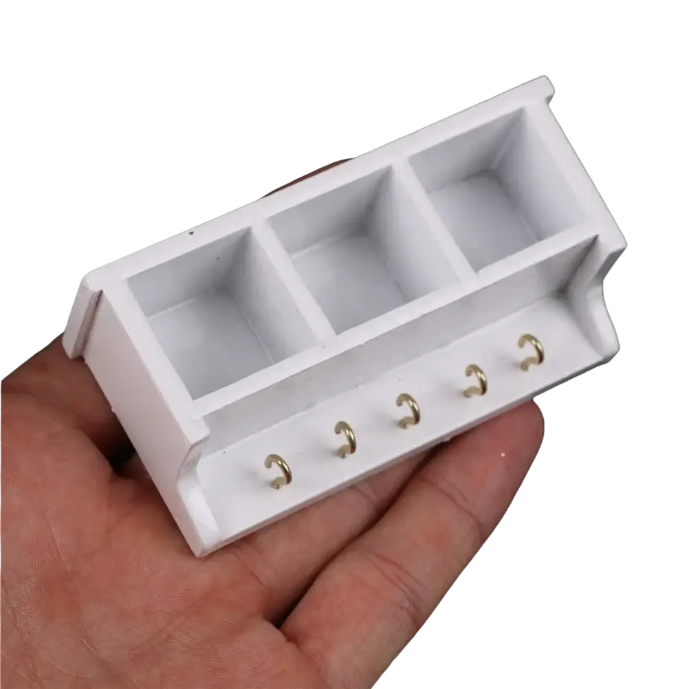 Dollhouse miniature white wall rack with three square compartments and five gold-colored hooks for organizing small items