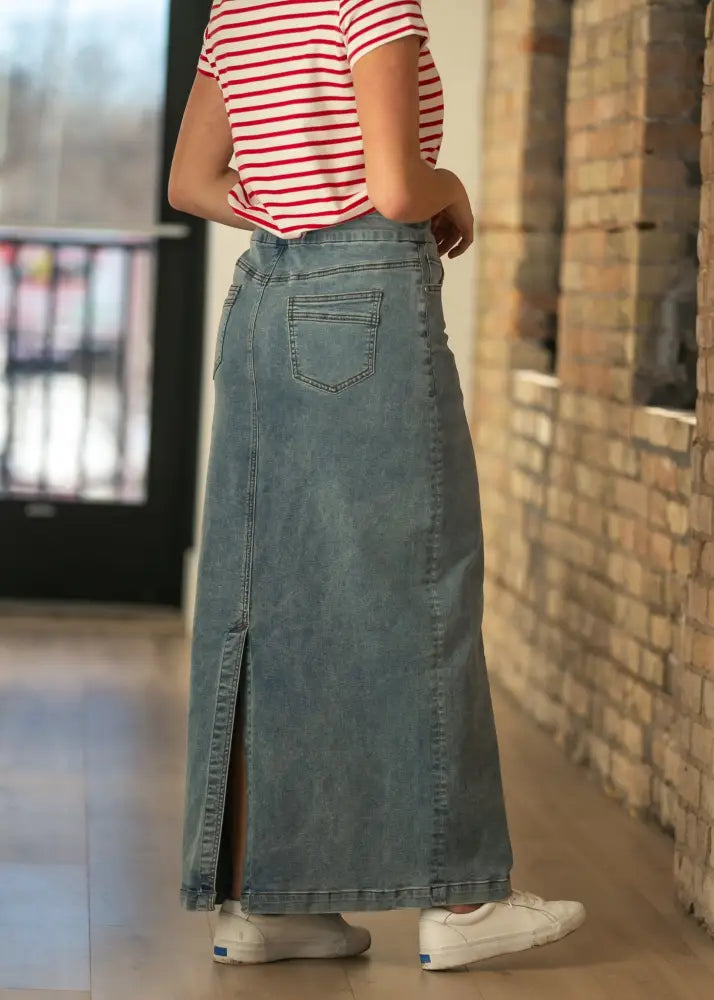 Donna classic wash stretch denim maxi skirt in light wash with front slit and back pocket shown from the back side