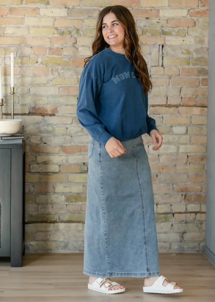 Blue long-sleeved sweatshirt with mom embroidered in lighter shade paired with donna classic wash stretch denim maxi skirt with pockets