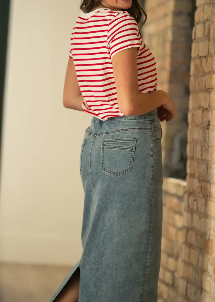 A mid-thigh length denim skirt in classic wash with stretch fabric and subtle fading shown from the back side