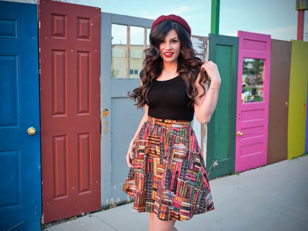 A woman wearing a vintage book print cotton a-line skirt with pockets in patchwork earthy tones and a black top