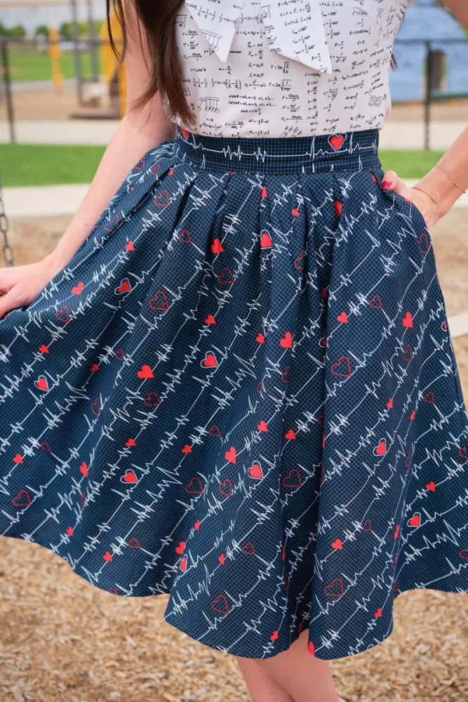 A navy pleated skirt with red heart and white electrocardiogram patterns featuring pockets from Doris