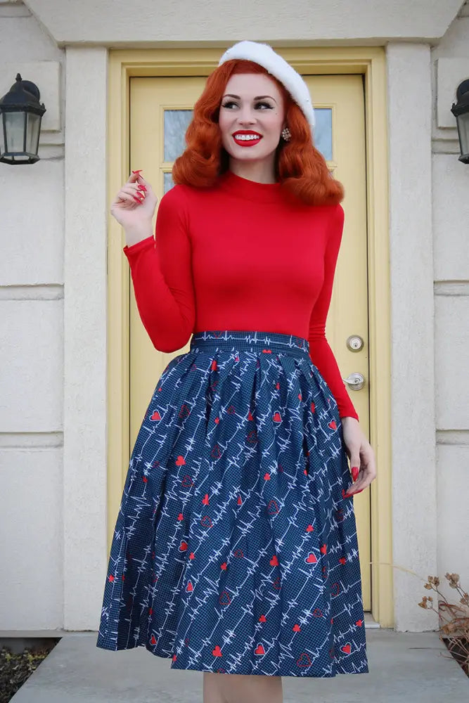 Doris navy pleated heartbreaker skirt with white barbed wire and red rose pattern worn with bright red long sleeve top