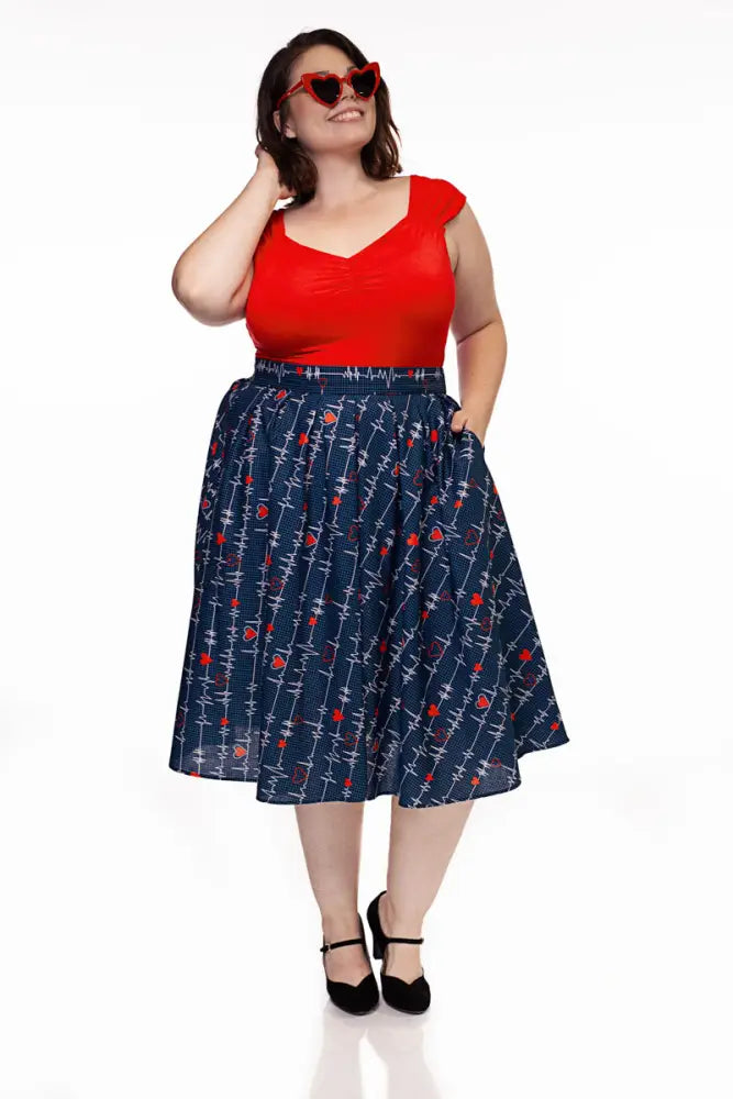 A navy pleated Doris heartbreaker skirt with white barbed wire and red rose pattern paired with a red top