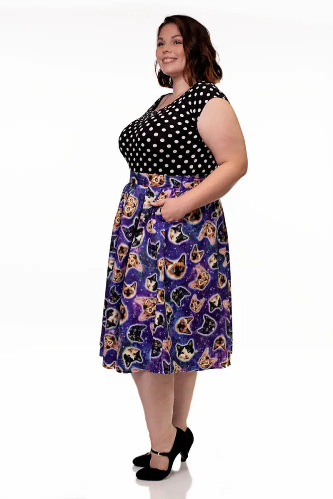 A plus-size woman wears a space cats galaxy print vintage purple a line skirt paired with a black and white polka dot top