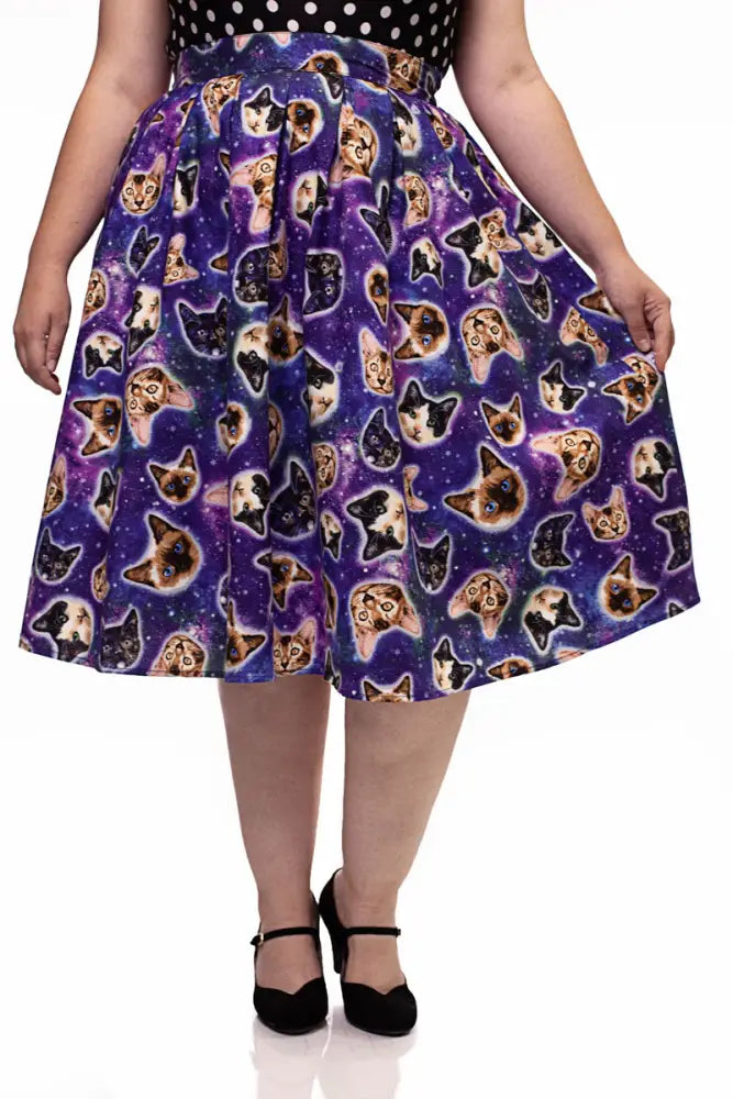 A vibrant purple a-line skirt with a repeating cat face pattern on a cosmic galaxy backdrop vintage style