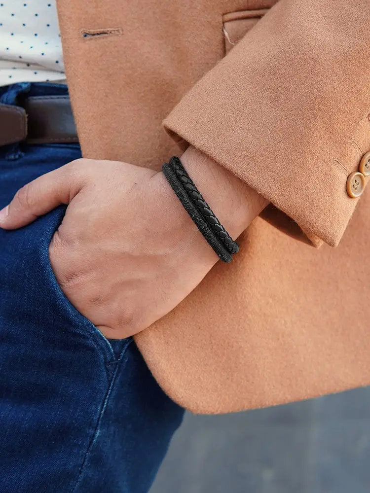 Black braided leather bracelet with double black suede and steel accents worn on a wrist