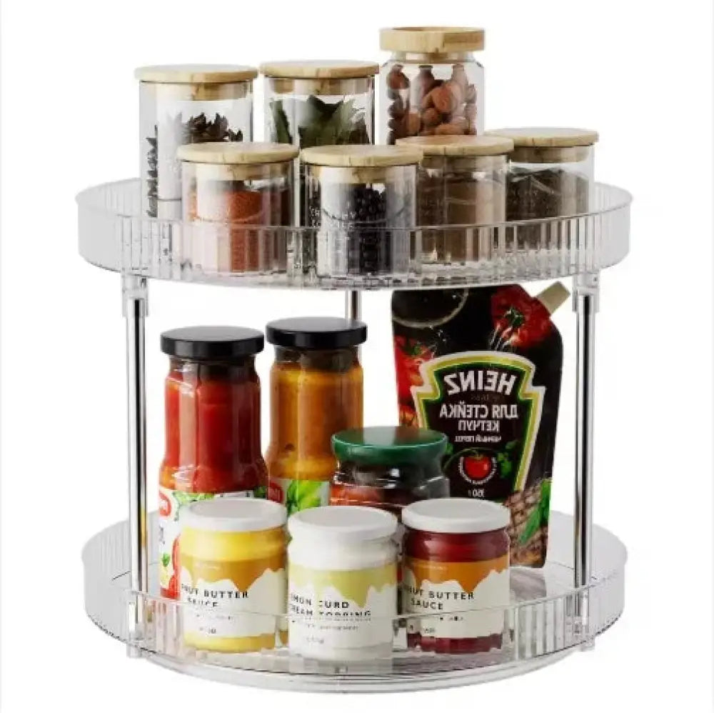 Clear two-tier acrylic rotating spice rack with transparent shelves and silver metal supports for vanity organization
