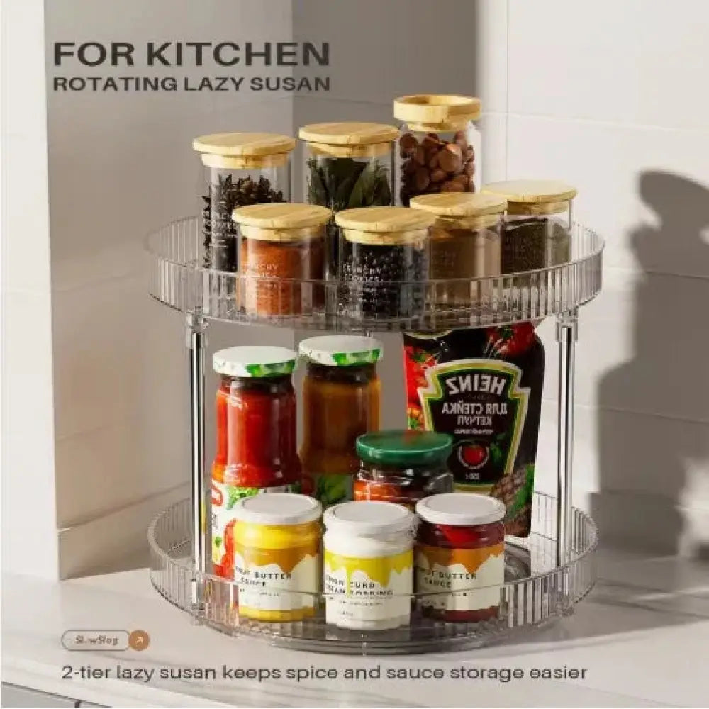 Clear two-tier acrylic rotating spice rack with transparent shelves and metallic frame holding spice jars and sauce bottles