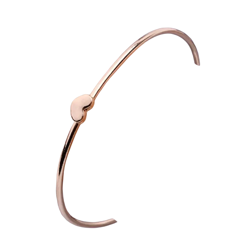 Gold-toned metal double ring bangle bracelet with a small smooth heart-shaped charm in a polished finish