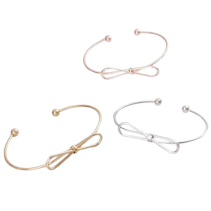 Three delicate open-ended double ring metal bangle bracelets with minimalist bow design in gold, rose gold, and silver tones