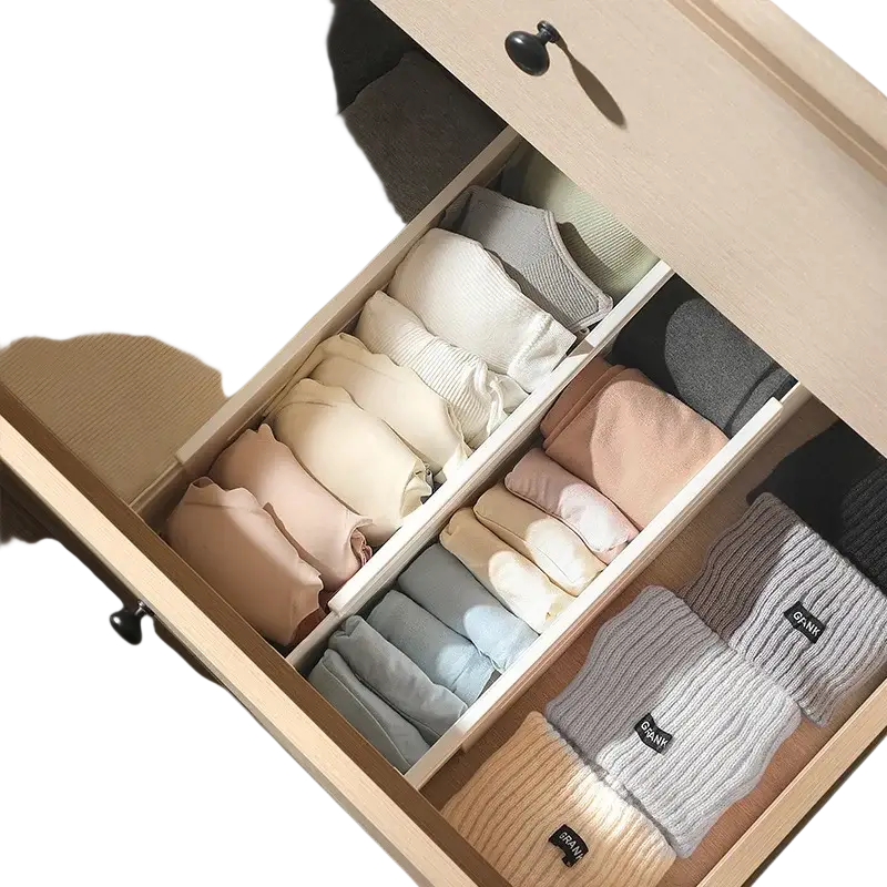 Organized drawer with pastel and neutral knit sweaters separated by expandable plastic drawer organizer divider