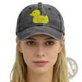 A faded gray distressed denim baseball cap featuring a bright yellow embroidered duck on the front