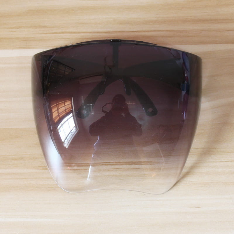 A multifunctional anti-splash iridescent shield sunglasses motorcycle face shield with a sleek gradient tint transitioning from dark purple to clear and smooth curved edges.