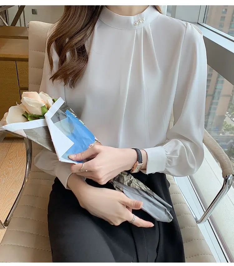 Blouse ample en satin blanc cassé pour femmes, à encolure haute et accents délicats de boutons perle au niveau du col.