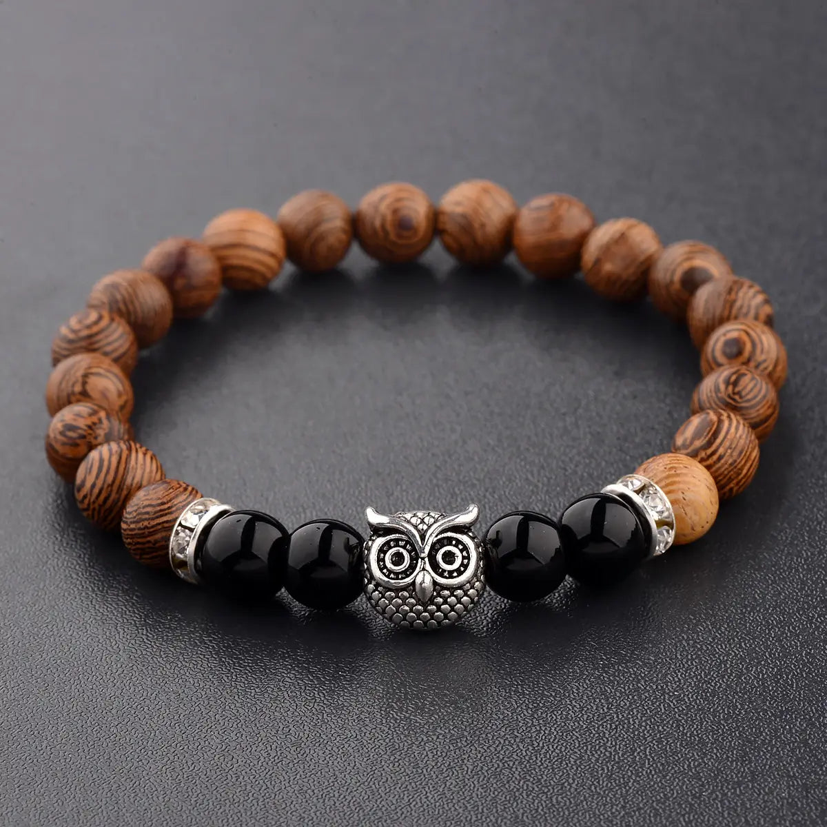 A crystal owl charm wood and onyx beaded bracelet featuring a silver owl charm with natural warm brown wood beads and smooth polished black onyx stones.