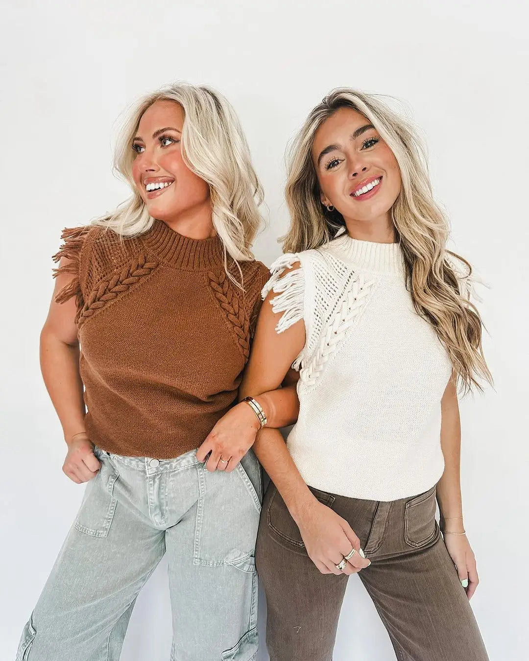 Two women wearing hand-woven fringed sleeveless knit sweater vests in brown knitted with braided detailing and white crochet materials.