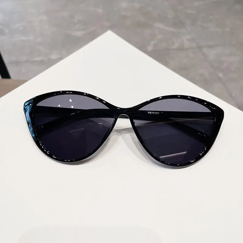 Lunettes de soleil œil-de-chat noires à monture brillante et verres UV380 gris foncé, conçues pour un usage mode léger.
