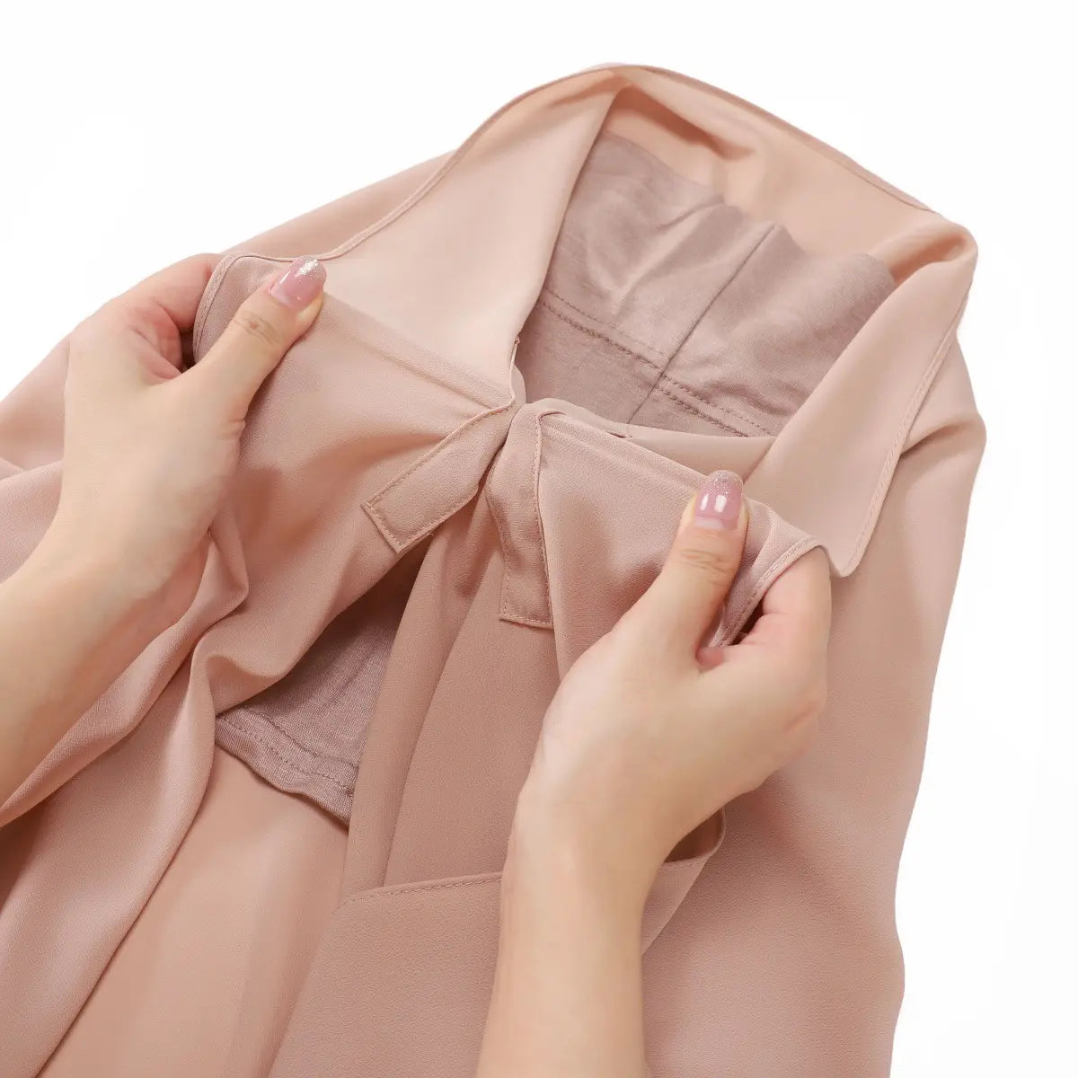 Un chemisier en satin rose poudré doux, à col structuré et à des détails de couture subtils, associé à un hijab magnétique en mousseline de couleur unie kaki.