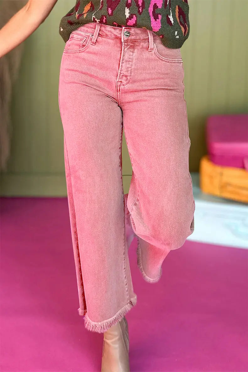 Jean rose à taille haute en denim effiloché à jambes larges, présentant un tissu en denim rose et une coupe à jambes larges, avec des ourlets effilochés.