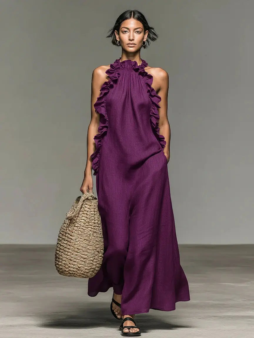 Une robe de villégiature longue maxi à encolure licou dos nu, couleur violet profond, avec des détails à volants le long de l’encolure et des manches.