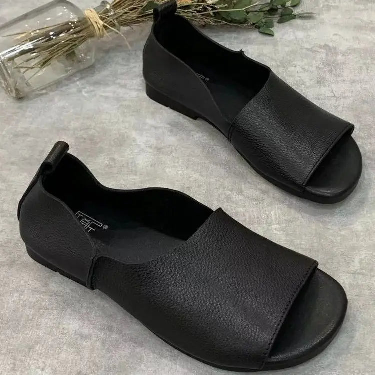 Sandalias de cuero color negro tipo mocasín con diseño de punta descubierta y superficie blanda y texturizada, con suela blanda retro para un uso cómodo.