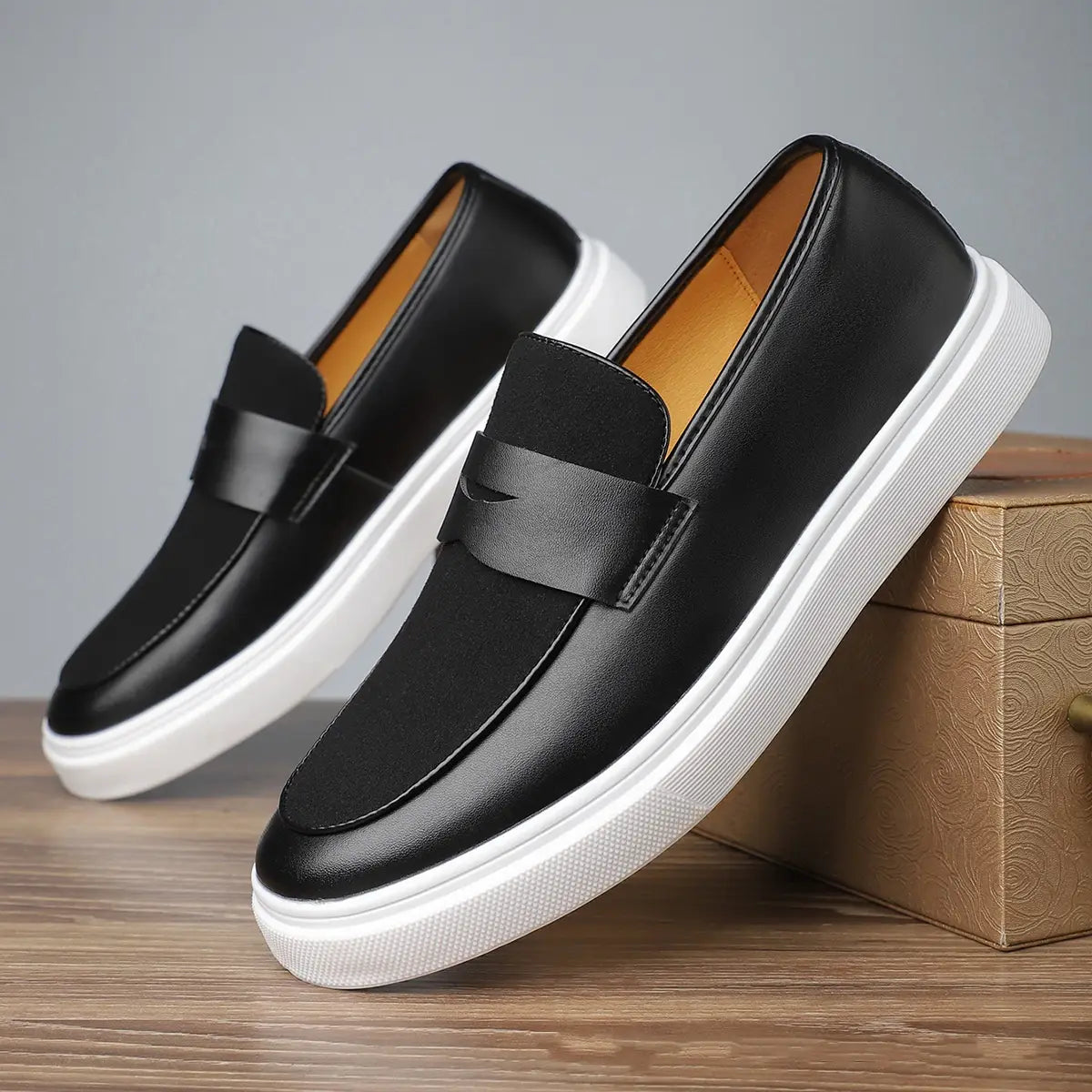 Herren-Leder-Slipper zum Hineinschlüpfen in Schwarz mit weißer Gummisohle und kontrastierender Innenauskleidung in Hellbraun.