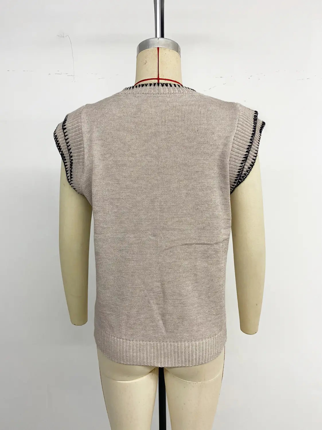 Haut sans manches en maille beige avec passepoil contrastant noir côtelé le long des emmanchures et de l’encolure, réalisé en tissu tricoté.