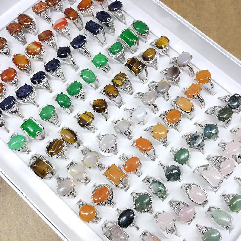 A collection of silver tone statement rings featuring natural colored gemstones in oval rectangular and round cuts.