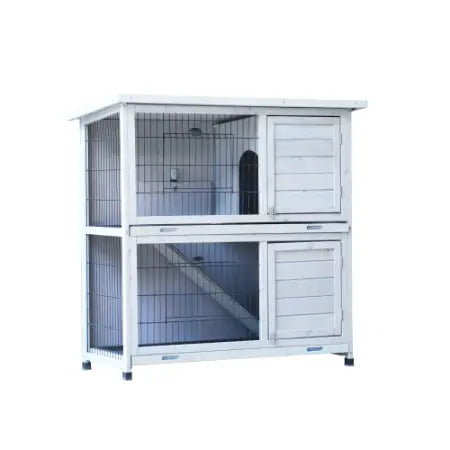 Cage en bois pour lapins à deux niveaux, blanche, avec côtés en treillis métallique et portes en panneaux en bois, conçue pour l’hébergement des lapins.