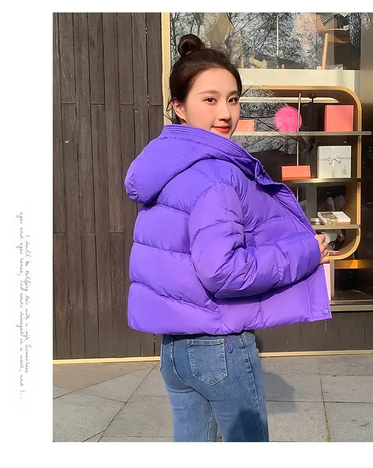 Woman hooded short down jacket in vibrant purple quilted puffer style with a hood for cold weather.