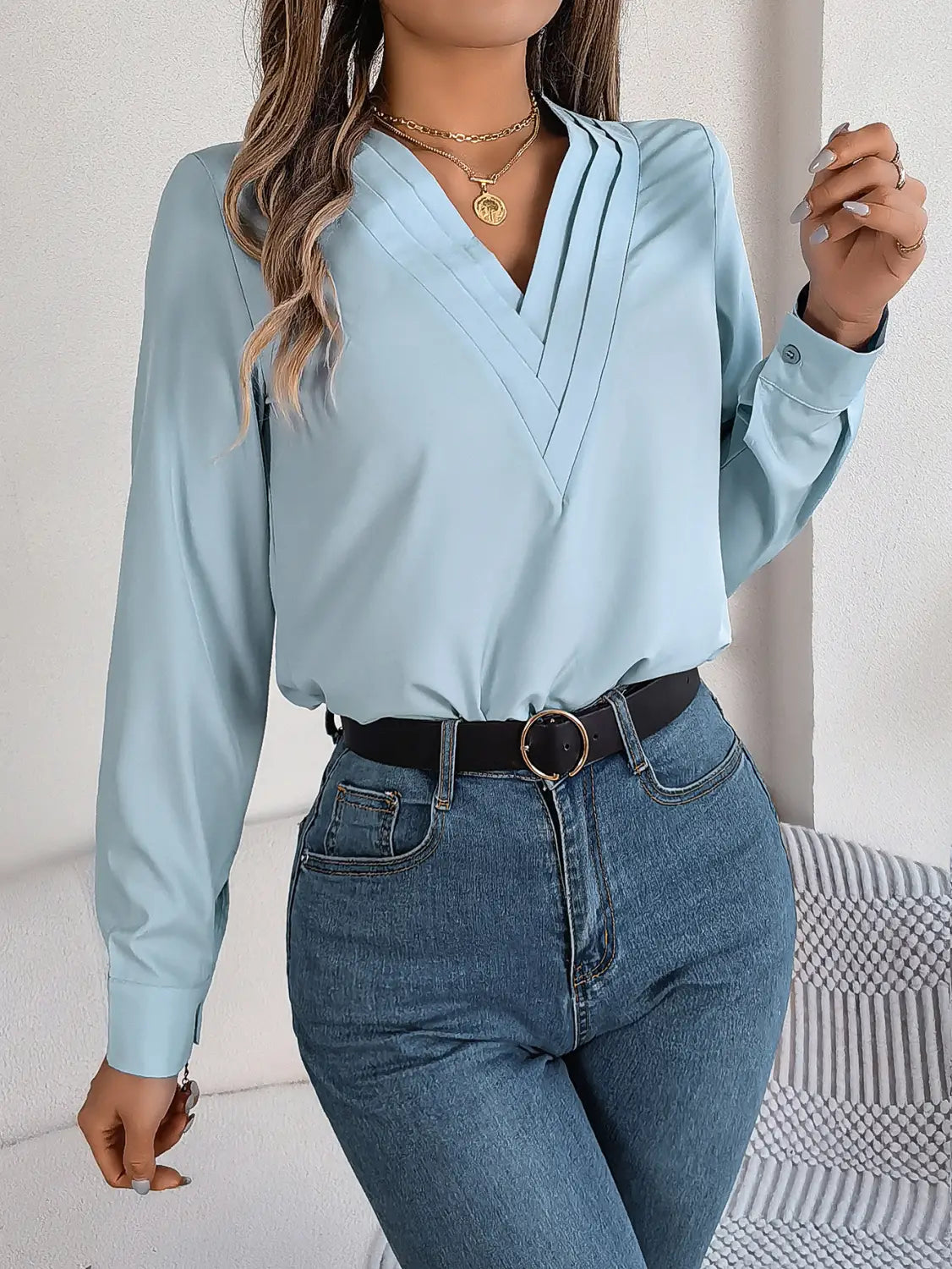 light blue satin blouse with long sleeves and v neck wrap style featuring black trim