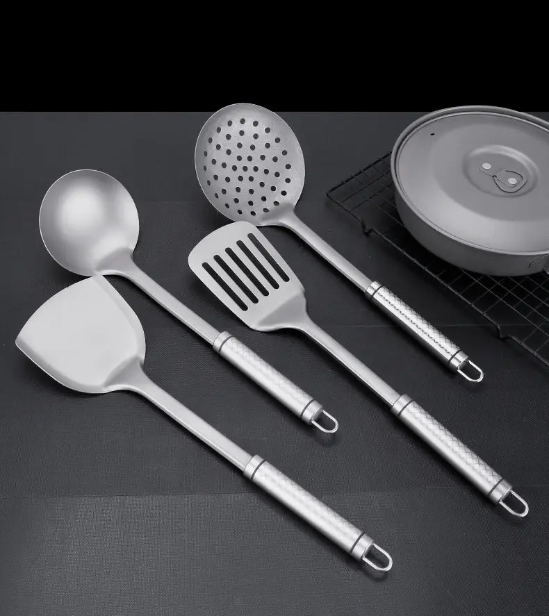 Lot de quatre spatules pour wok en titane et d’ustensiles de cuisine en acier inoxydable, avec des poignées texturées et des extrémités en forme de boucles.