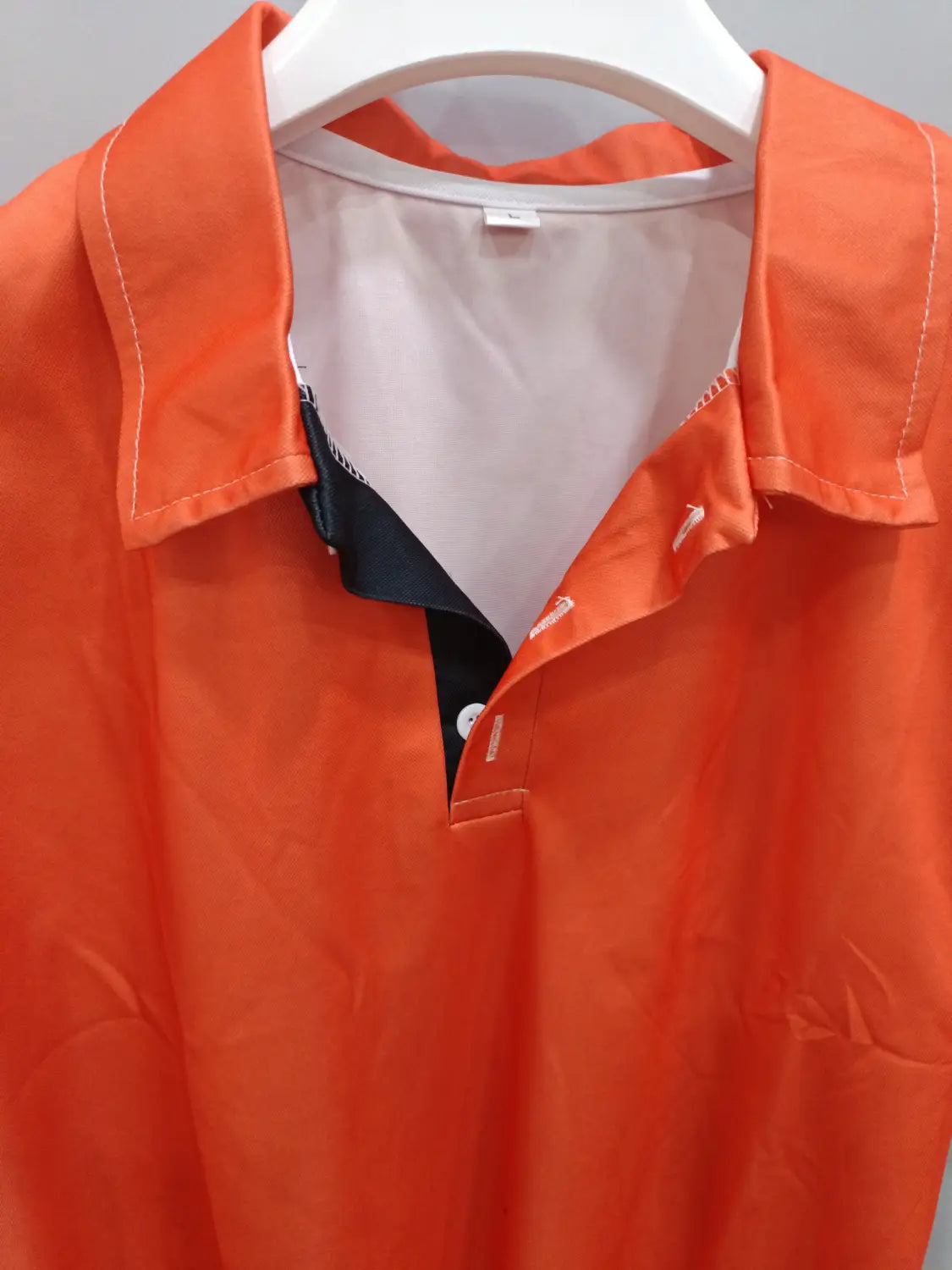 Kontrastiertes Herren-Poloshirt mit auffällig orangefarbenem kurzem Ärmel und Knopfverschluss-Design, mit schwarzem Innenkragen und weißer Ziernaht entlang der Knopfleiste.