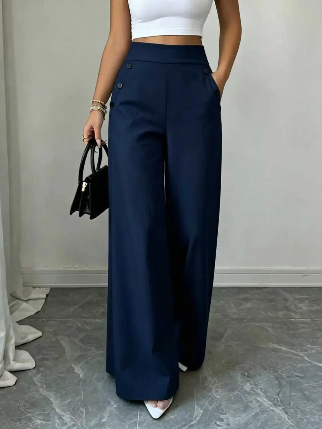 Pantalon ample taille haute bleu marine réalisé dans une matière souple, avec des détails de boutons sur les poches avant.